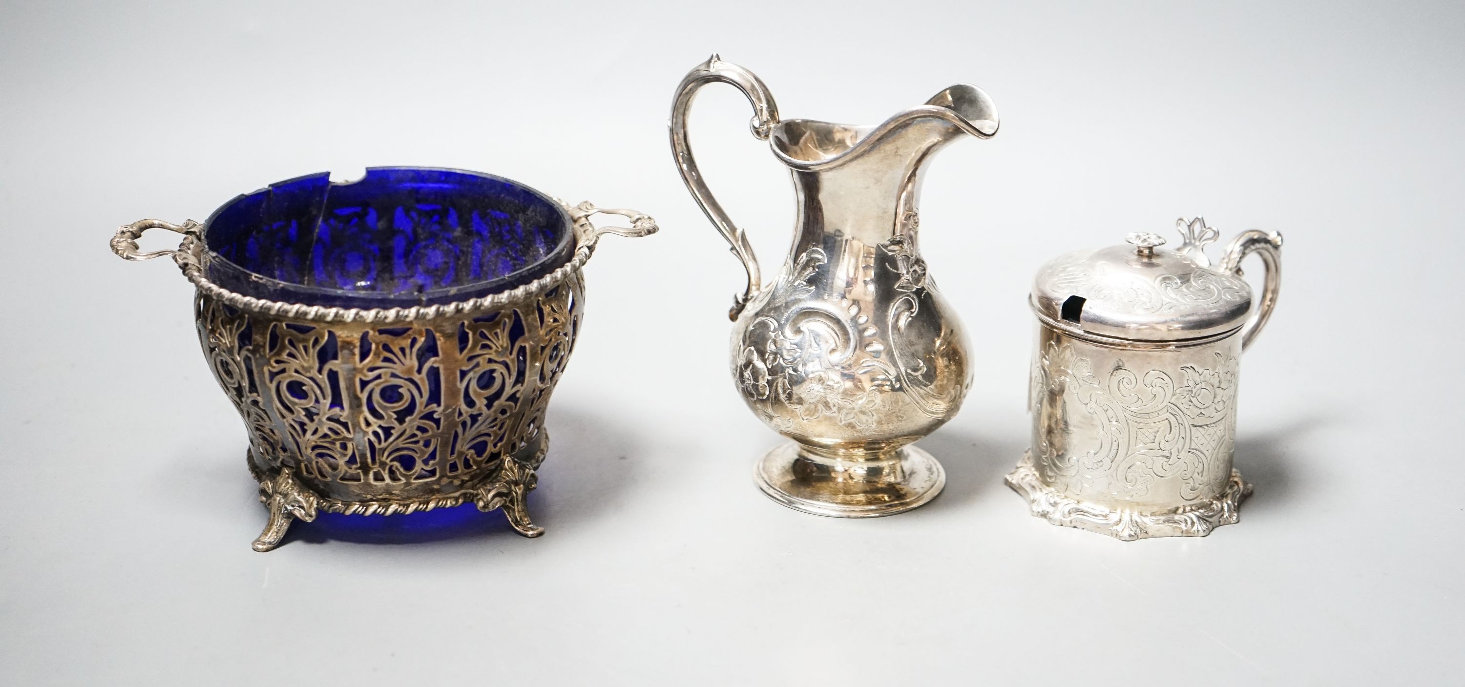 A Victorian silver cream jug, London, 1851, a Victorian silver mustard and a 1930's pierced silver two handled bowl, with blue glass liner.